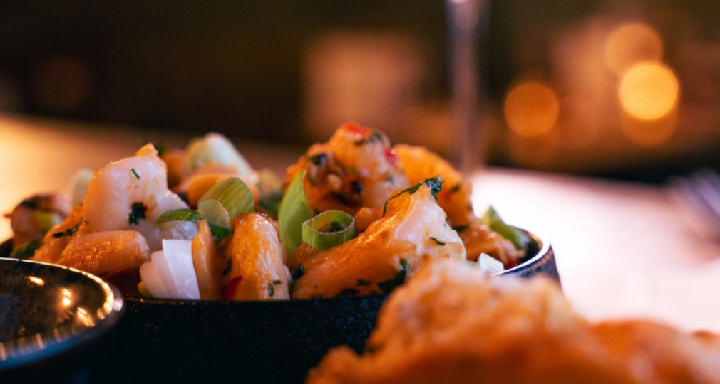 Een close-up van een smakelijk gerecht met gebakken groenten, geserveerd met een glas witte wijn op tafel.