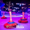 Verlicht ijsbaanscène met kegels en een persoon die curling speelt tijdens een avondwedstrijd.