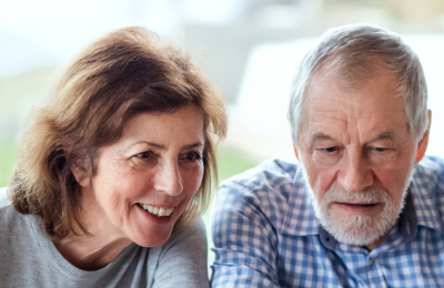 Twee oudere mensen glimlachen terwijl ze samen een schaakspel spelen in een gezellige wijkkamer van Avedan.