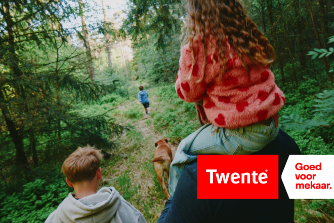 Kinderen wandelen met een hond in een groen bos, met het logo en de slogan 'Twente - Goed voor mekaar.'