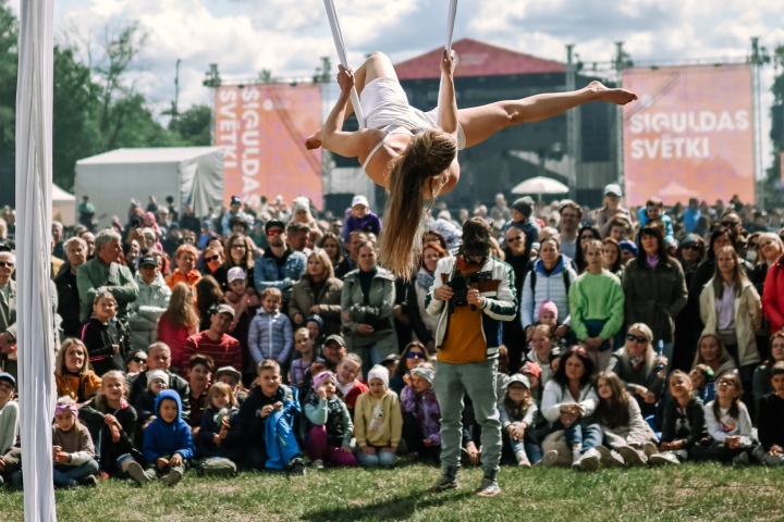 Een acrobaat voert een luchtvoorstelling uit voor een groot publiek op een buitenfestival.
