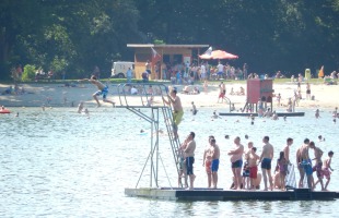 Drukke zwemsteiger met mensen die in de rij staan om van de duikplank te springen op een zonnige dag.